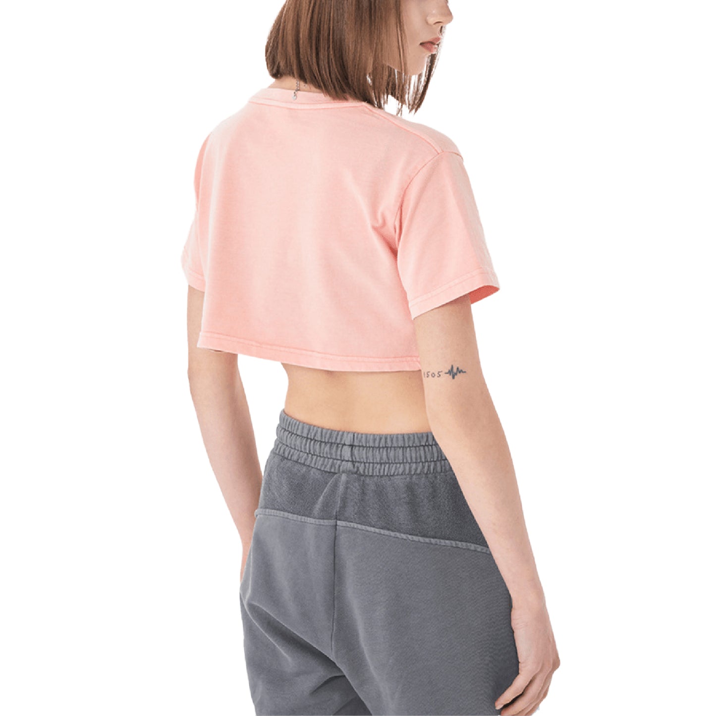 Woman wearing a pink crop top and gray sweatpants.