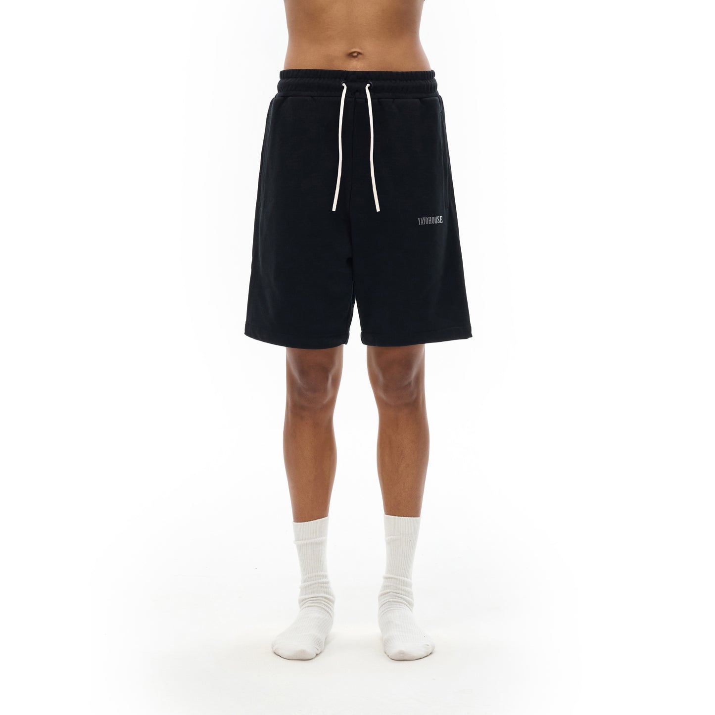 A person wearing black sweat shorts and white socks.