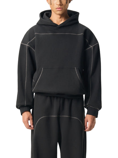 Person wearing a black hoodie and pants set on a white background