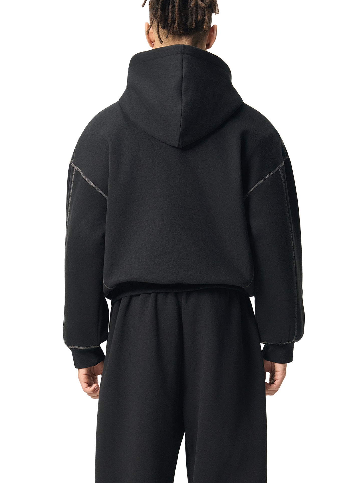 Person wearing a black hoodie and pants set on a white background
