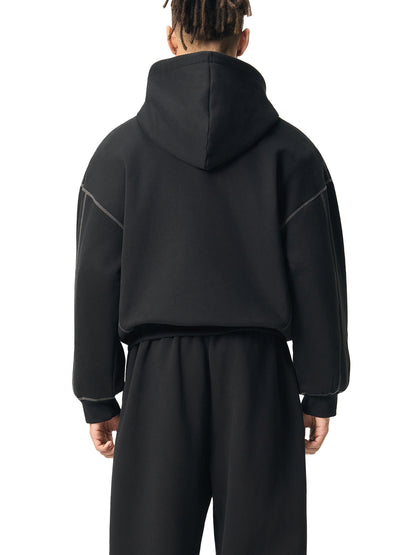 Person wearing a black hoodie and pants set on a white background