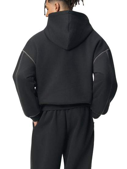 Person wearing a black tracksuit with gray accents on a white background