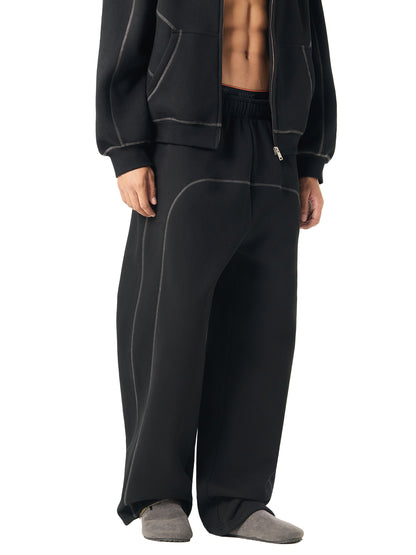 Person wearing black tracksuit pants and jacket on a white background