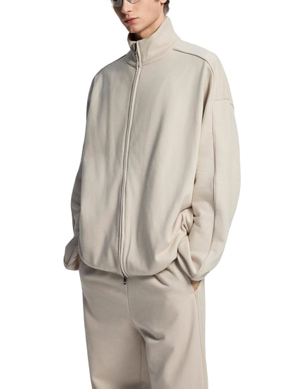 Person wearing a beige tracksuit on a white background