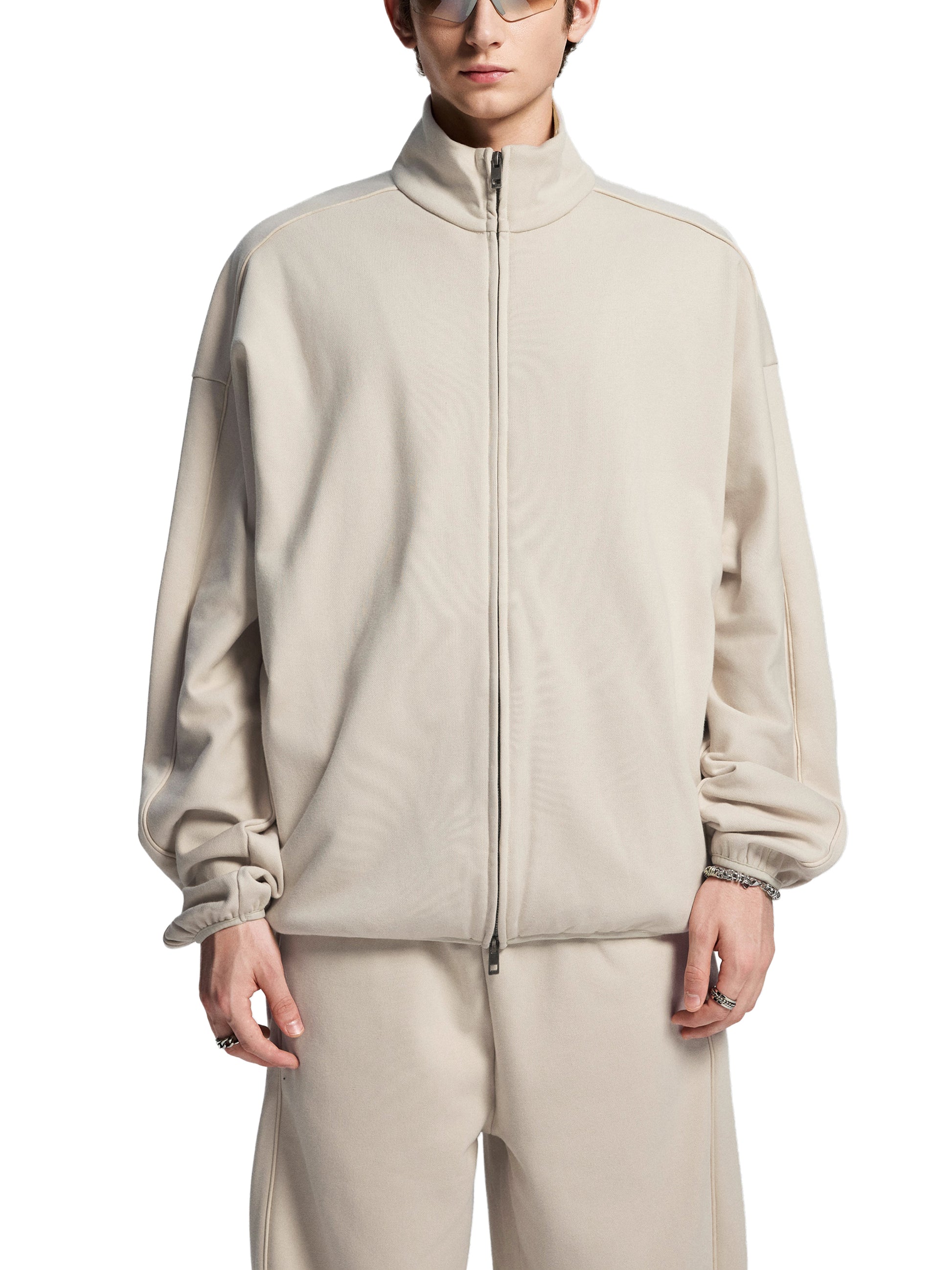 Person wearing a beige tracksuit on a white background