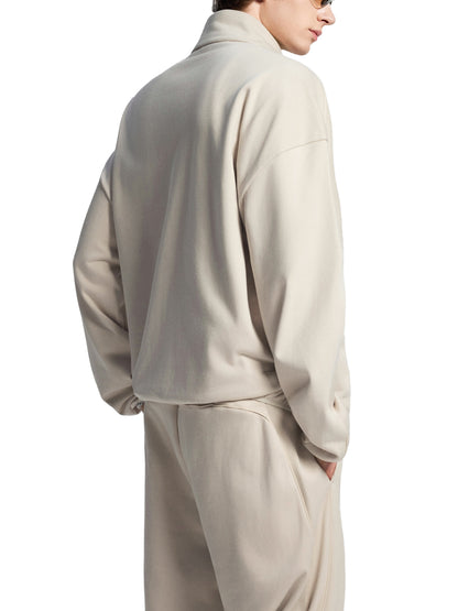 Person wearing a beige tracksuit on a white background