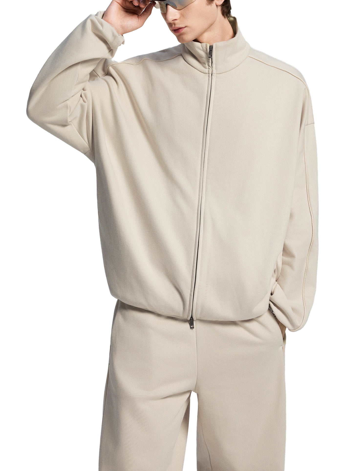 Person wearing a beige tracksuit on a white background