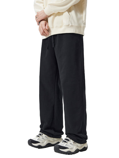 Person wearing a cream hoodie and black pants on a white background