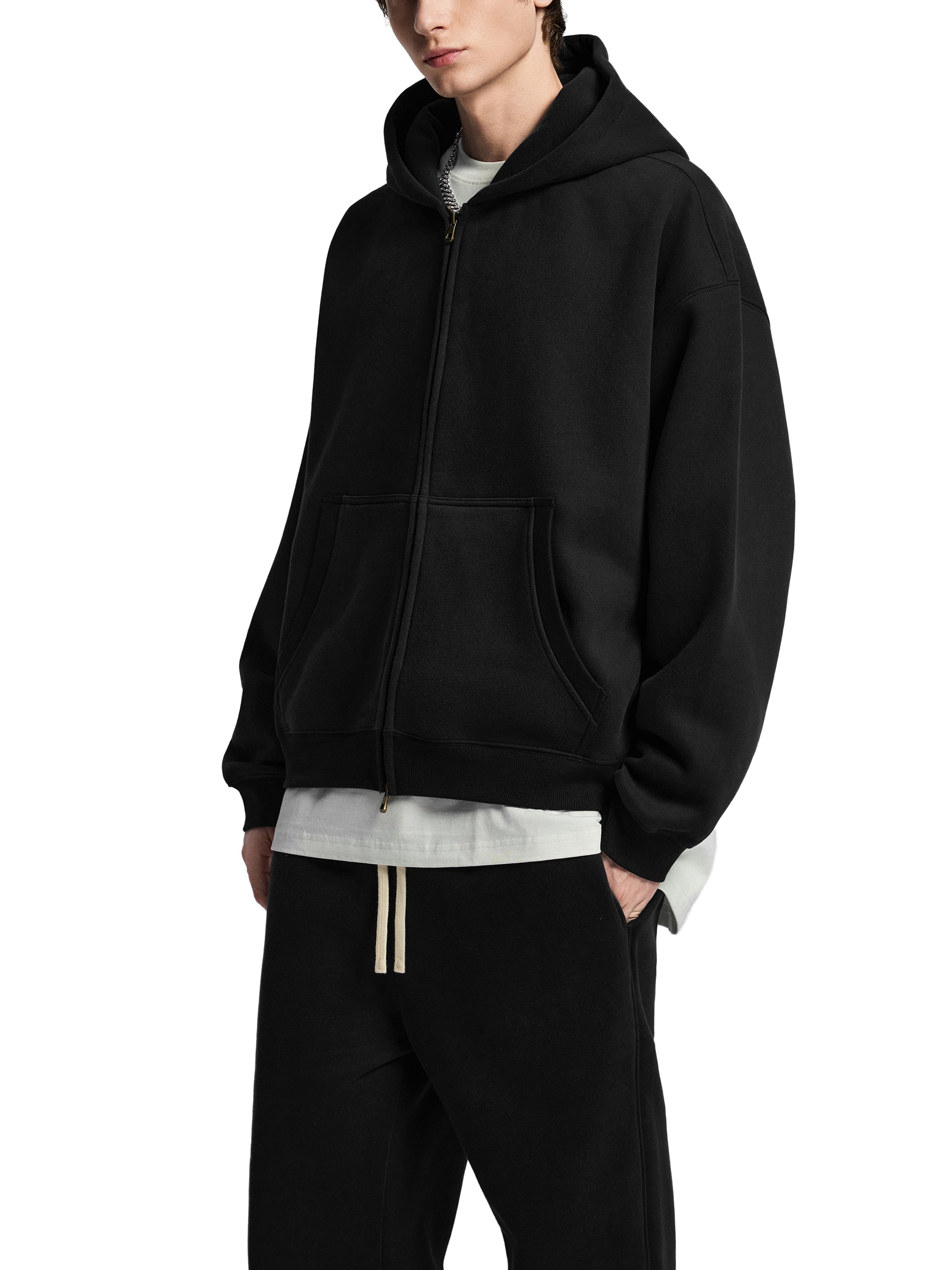 Person wearing a black hoodie and black pants on a white background