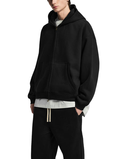 Person wearing a black hoodie and black pants on a white background