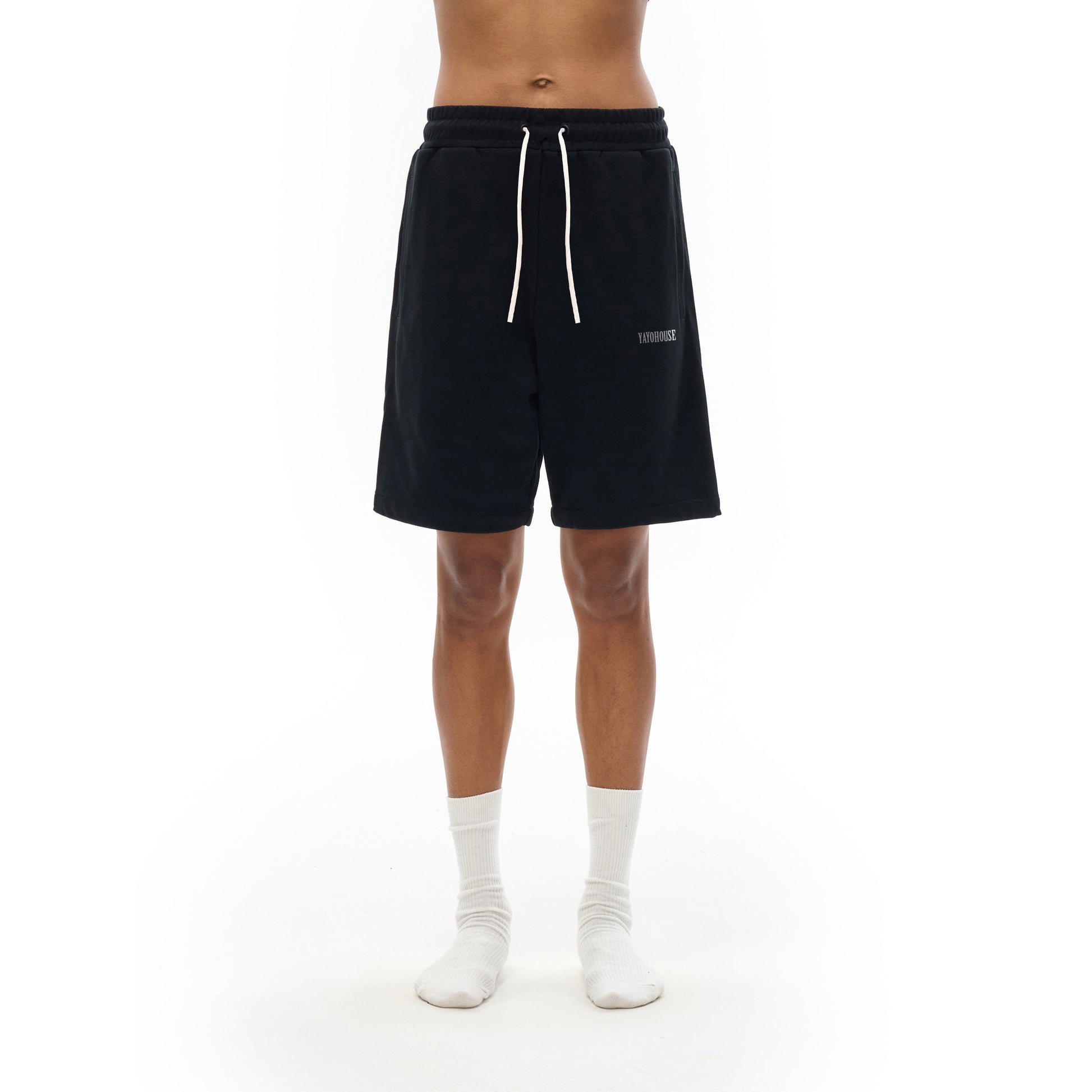 A person wearing black sweat shorts and white socks.