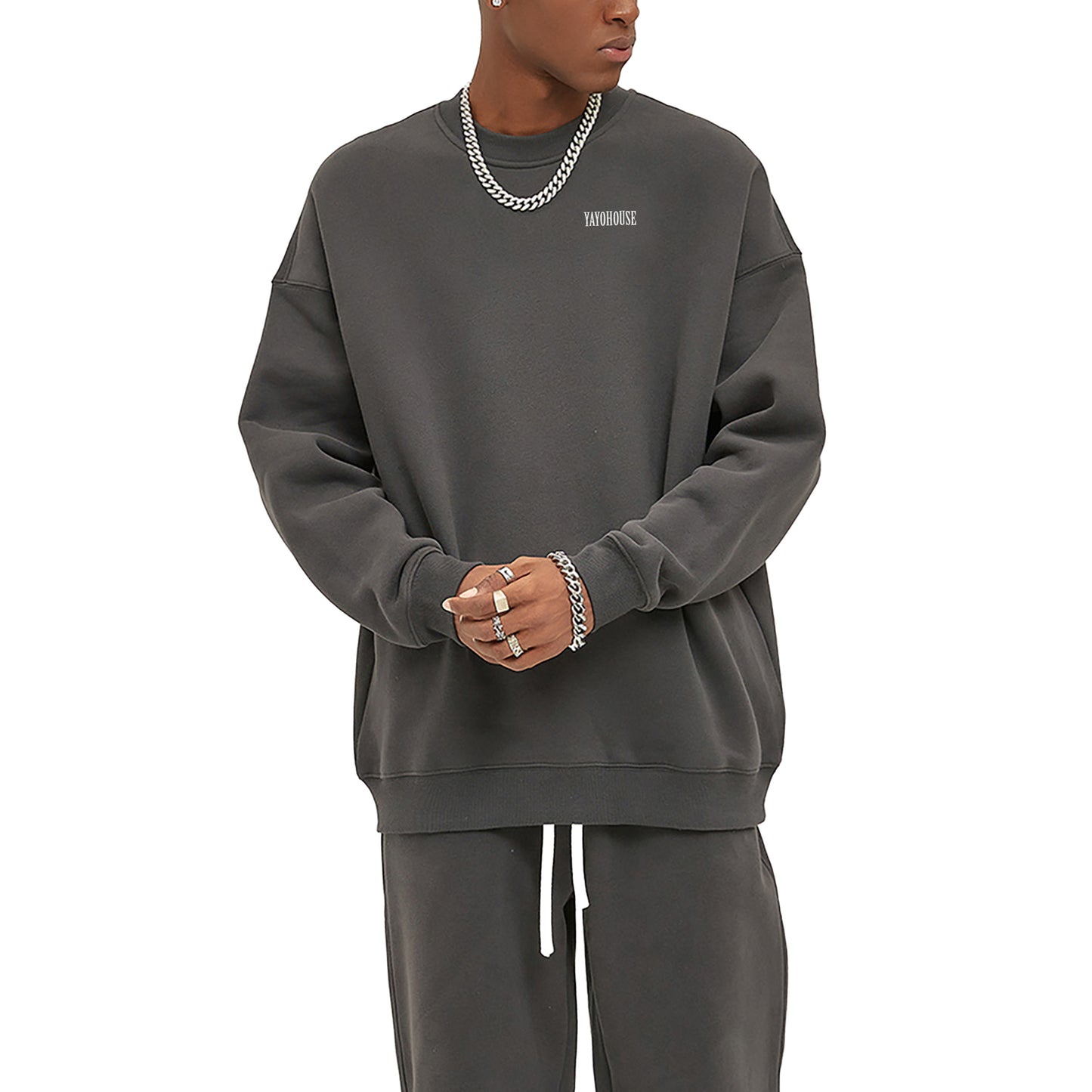 Man in gray sweatshirt and sweatpants, wearing silver jewelry.