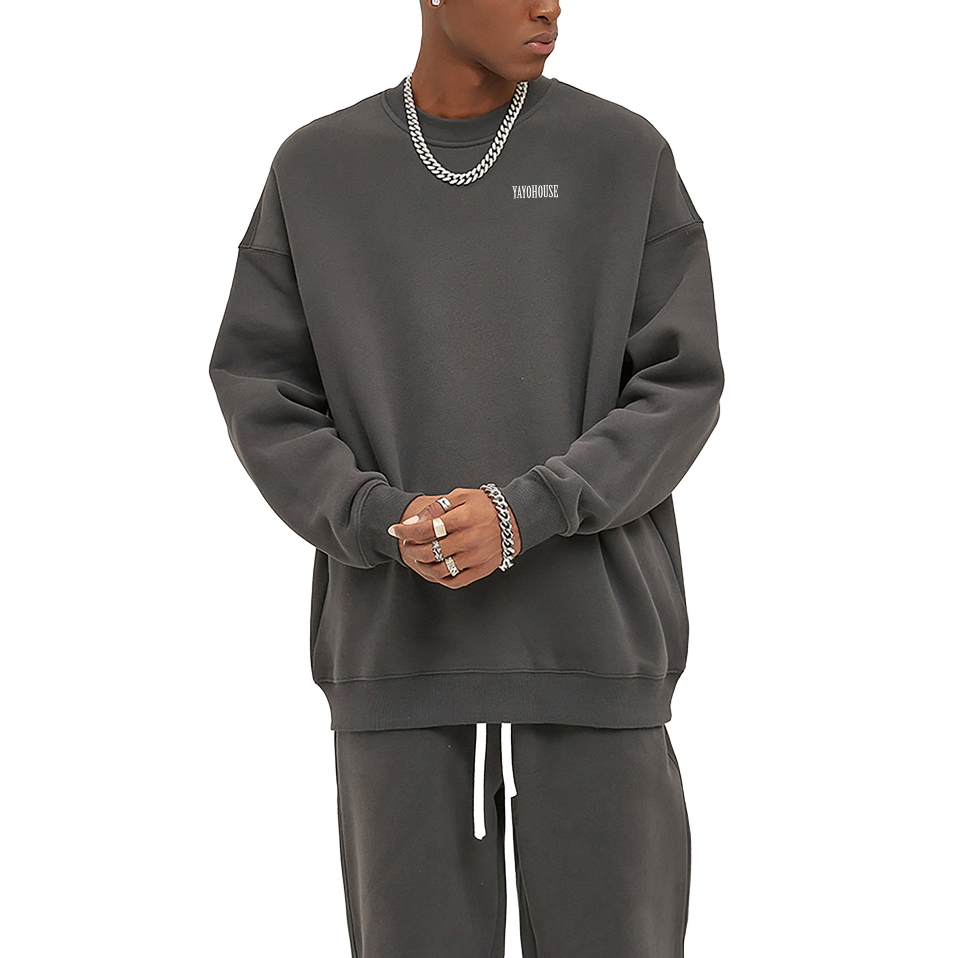 Man in gray sweatshirt and sweatpants, wearing silver jewelry.