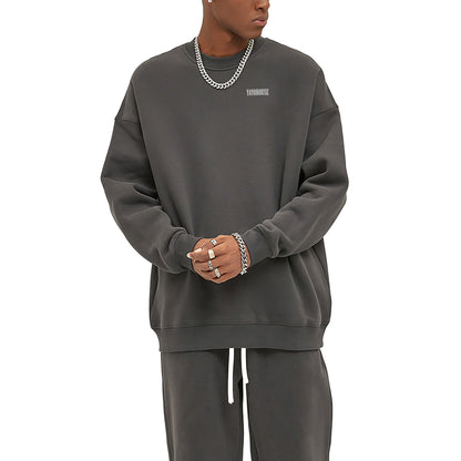 Man in gray sweatshirt and sweatpants, wearing silver jewelry.