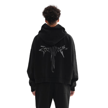 A person wearing a black hoodie and pants, standing with their back to the camera.